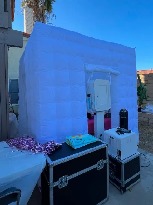 The inflatable photo booth cabin assembled outdoors, with the booth, fog machine and equipment cases